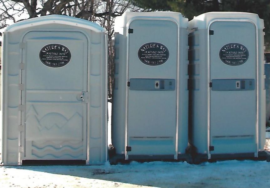 Three portable toilets are lined up in the snow