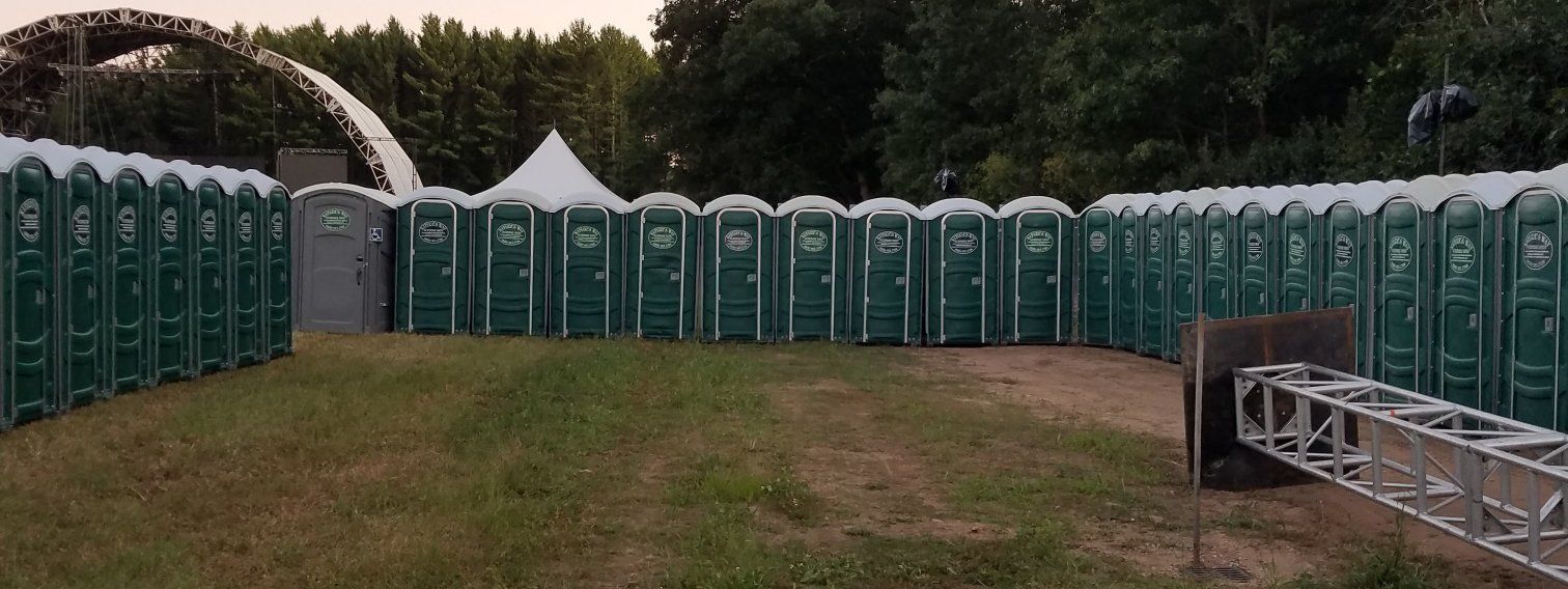 A row of portable toilets are lined up in a field