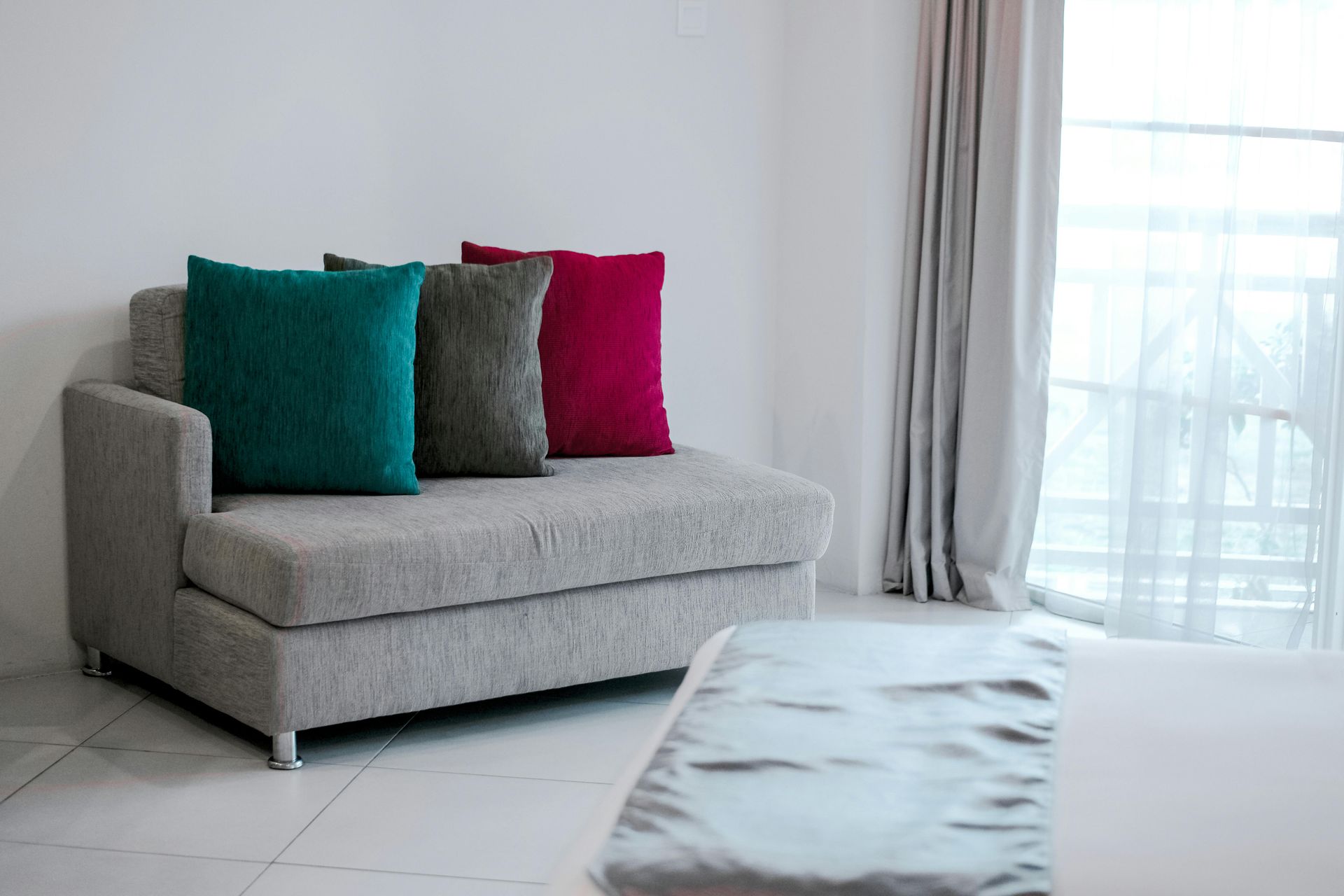 A couch with a lot of pillows on it in a living room next to a bed.