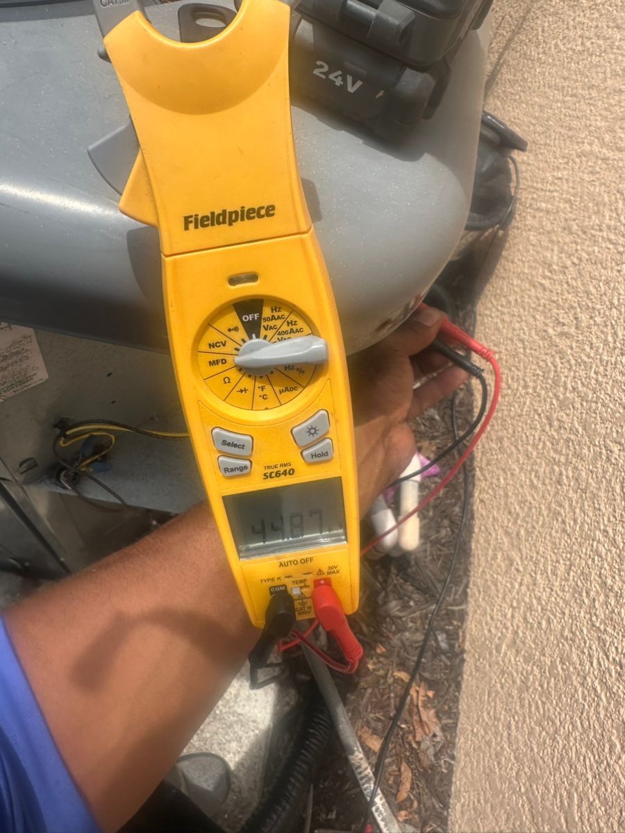 Handheld yellow Fieldpiece clamp meter measuring capacitor during maintenance siggs technician
