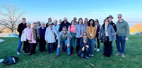 A group of people are posing for a picture on top of a grassy hill.