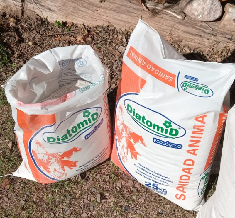 Dos sacos blancos de pienso Diatomid sobre suelo de tierra, uno abierto