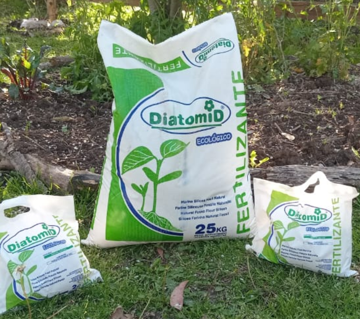Tres bolsas de fertilizante Diatomid sobre el césped, con una bolsa grande blanca y verde centrada en el exterior.