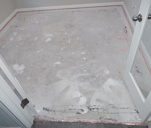 Bare concrete floor in a room, with white door frames and door. Red lines mark the perimeter.