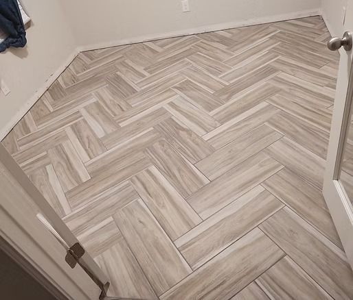 Herringbone tile floor in a room with light-colored walls and a partially open door.