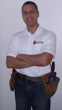 Man in white polo shirt with tool belt, arms crossed, smiling.