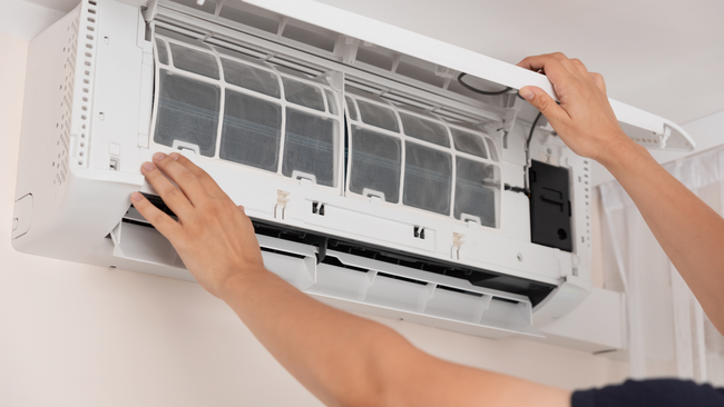 A person is cleaning a wall mounted air conditioner.