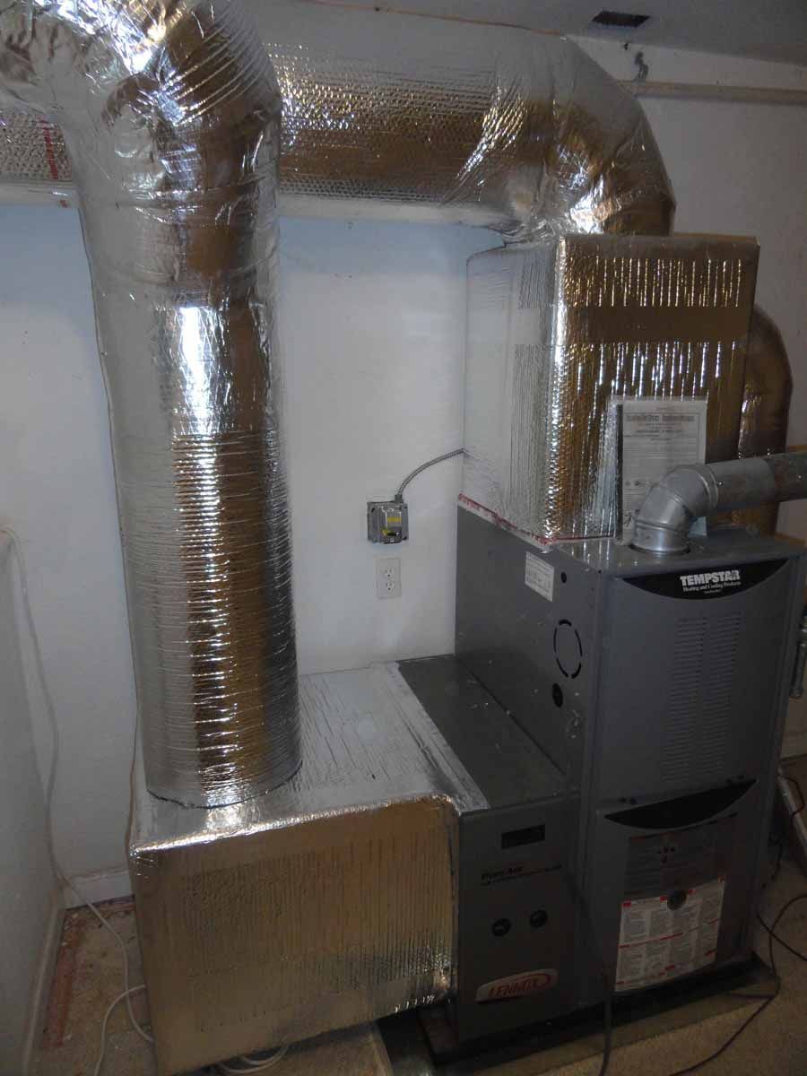 A furnace is sitting in a room next to a wall.