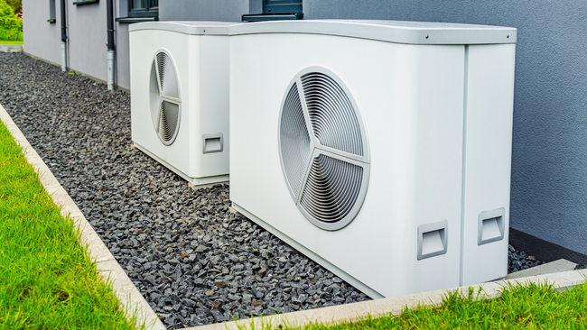 Two air conditioners are sitting next to each other on the side of a building.