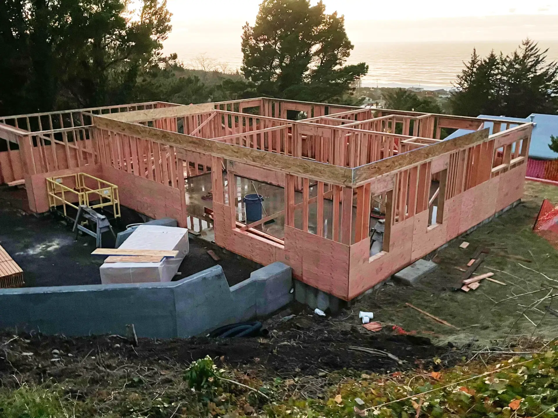 Partially built wooden house frame at a construction site at sunset