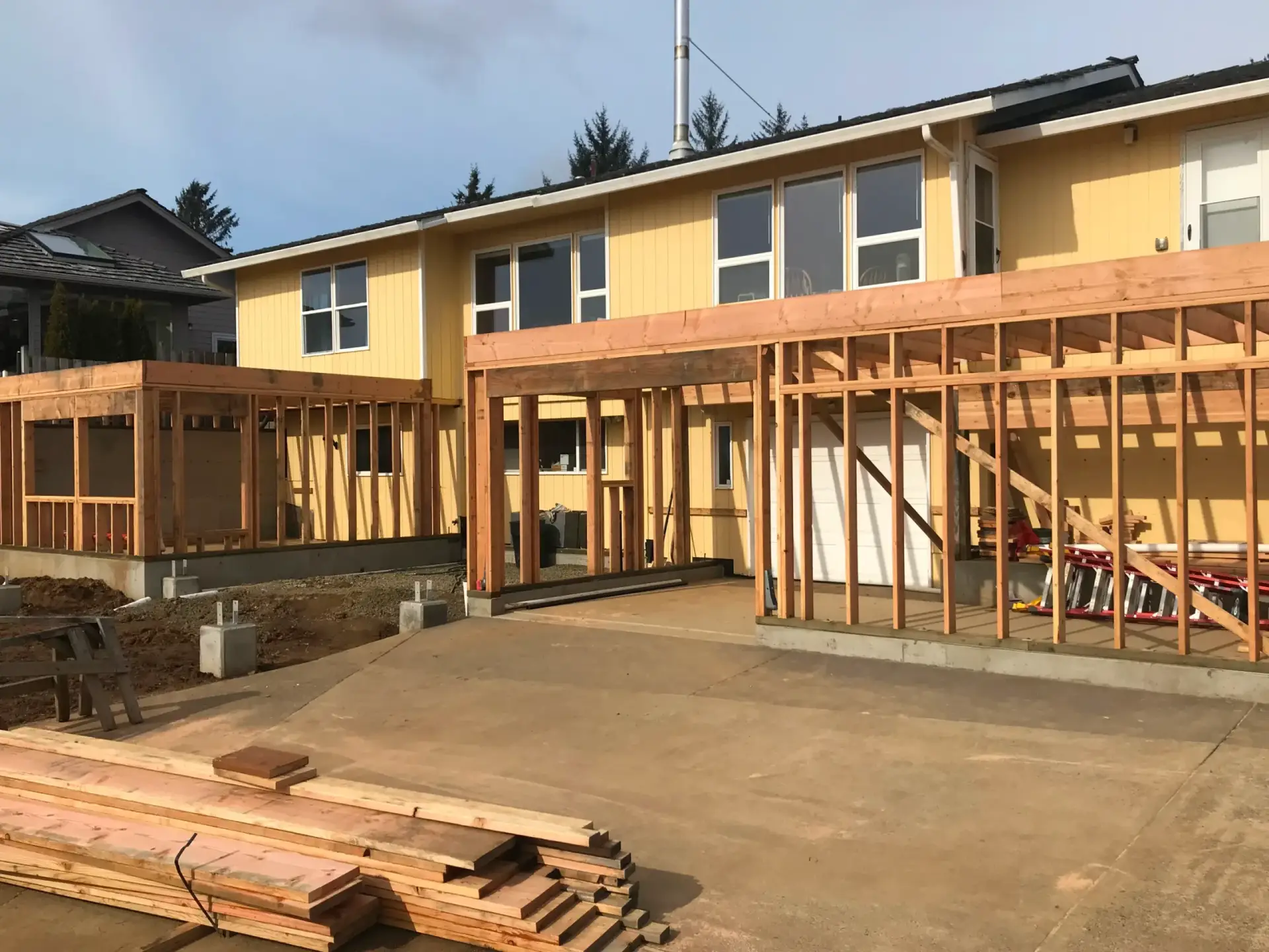 New house under construction with wood framing and a concrete patio in front