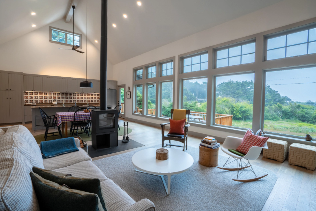Bright living room with large windows, mountain view, white sofa, round table, and hanging pendant lights