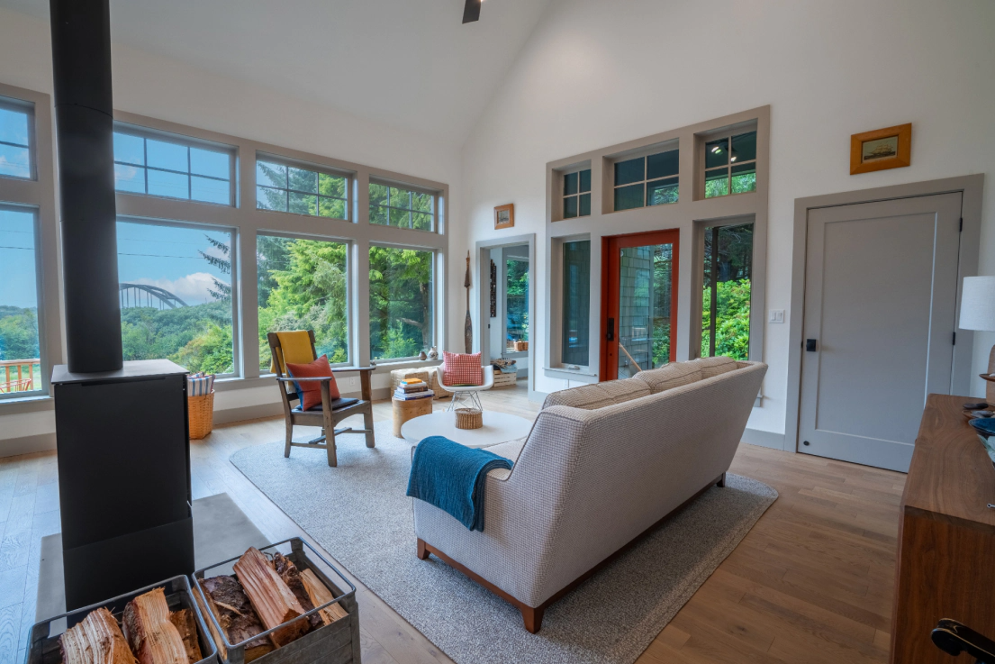 Bright living room with large windows, beige sofa, chairs, and a mountain view outside