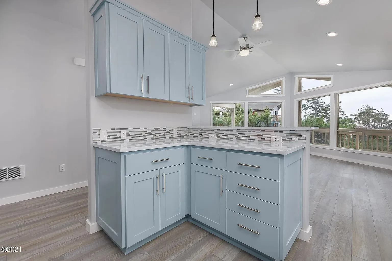 Light blue kitchen island and cabinets in a bright modern open-plan kitchen with large windows