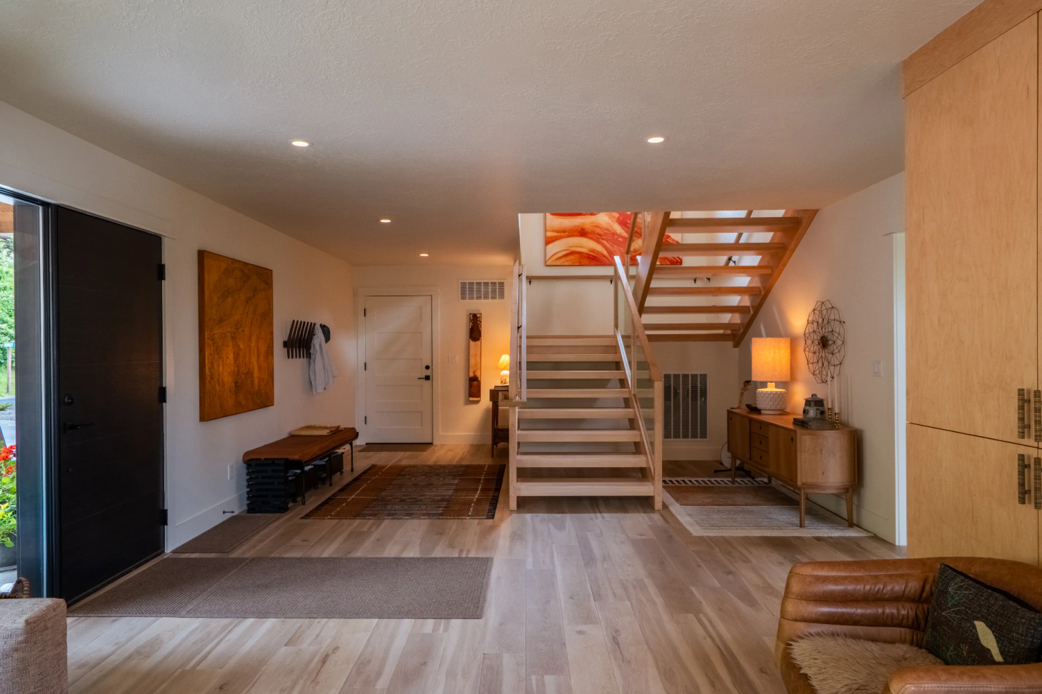 Modern loft living room with staircase, wood floors, and warm lighting