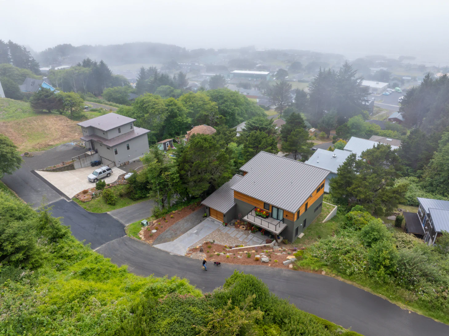 Misty hillside neighborhood with houses, trees, and winding roads