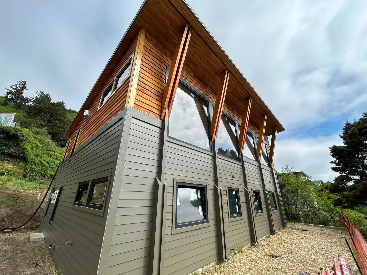 Modern two-story house with gray siding and wood upper exterior on a sloped hillside