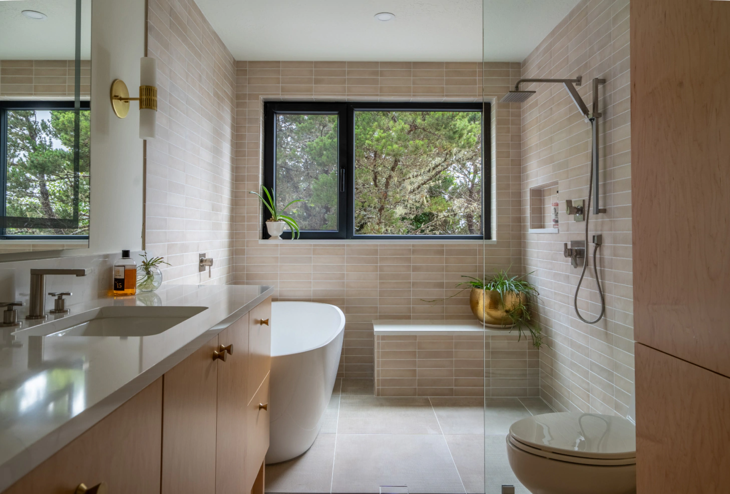 Modern bathroom with freestanding tub, vanity, shower, and large window with greenery outside