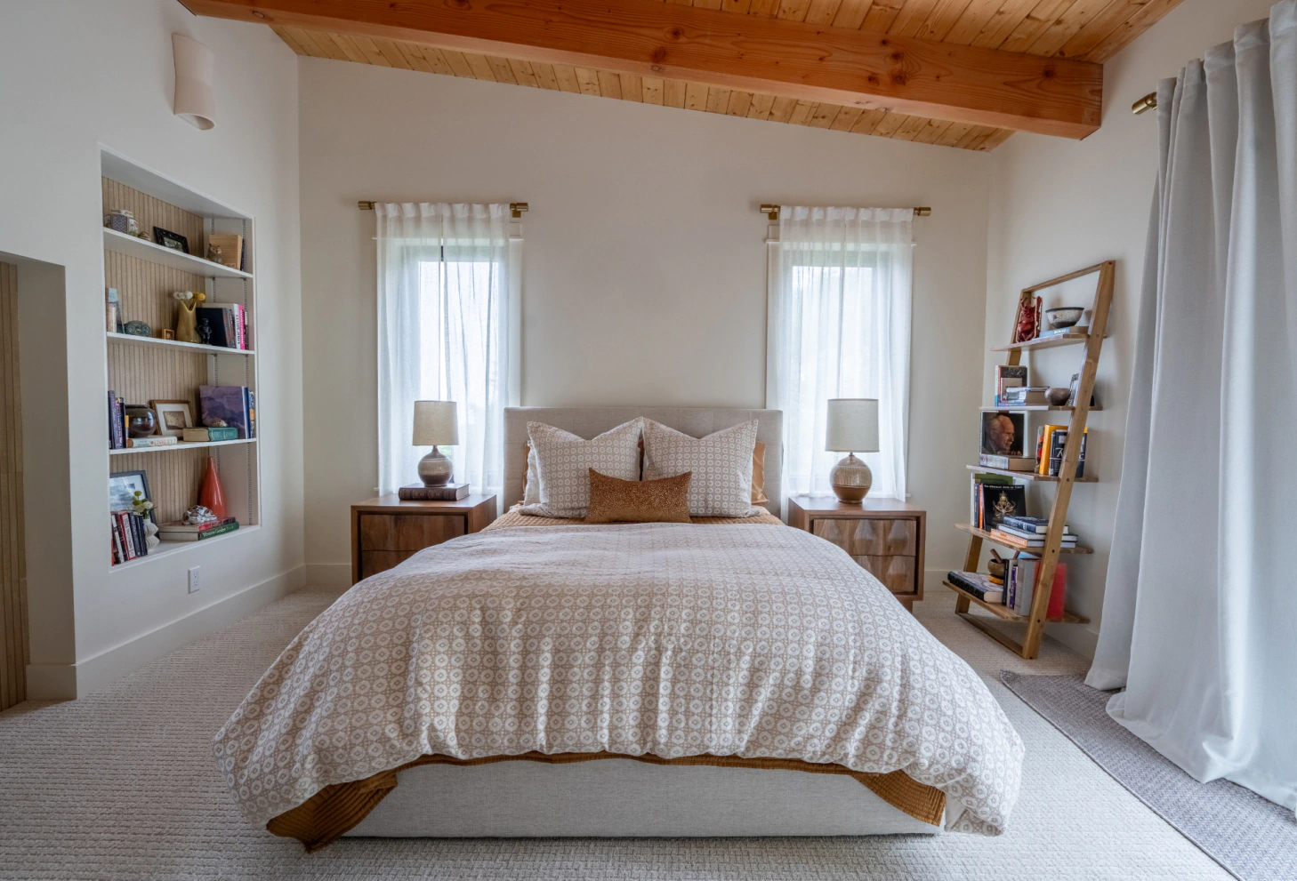 Bright cozy bedroom with a bed, wooden ceiling, two windows, and a white rug