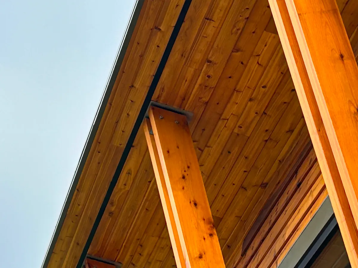 Wooden building eaves with vertical support beams against a blue sky