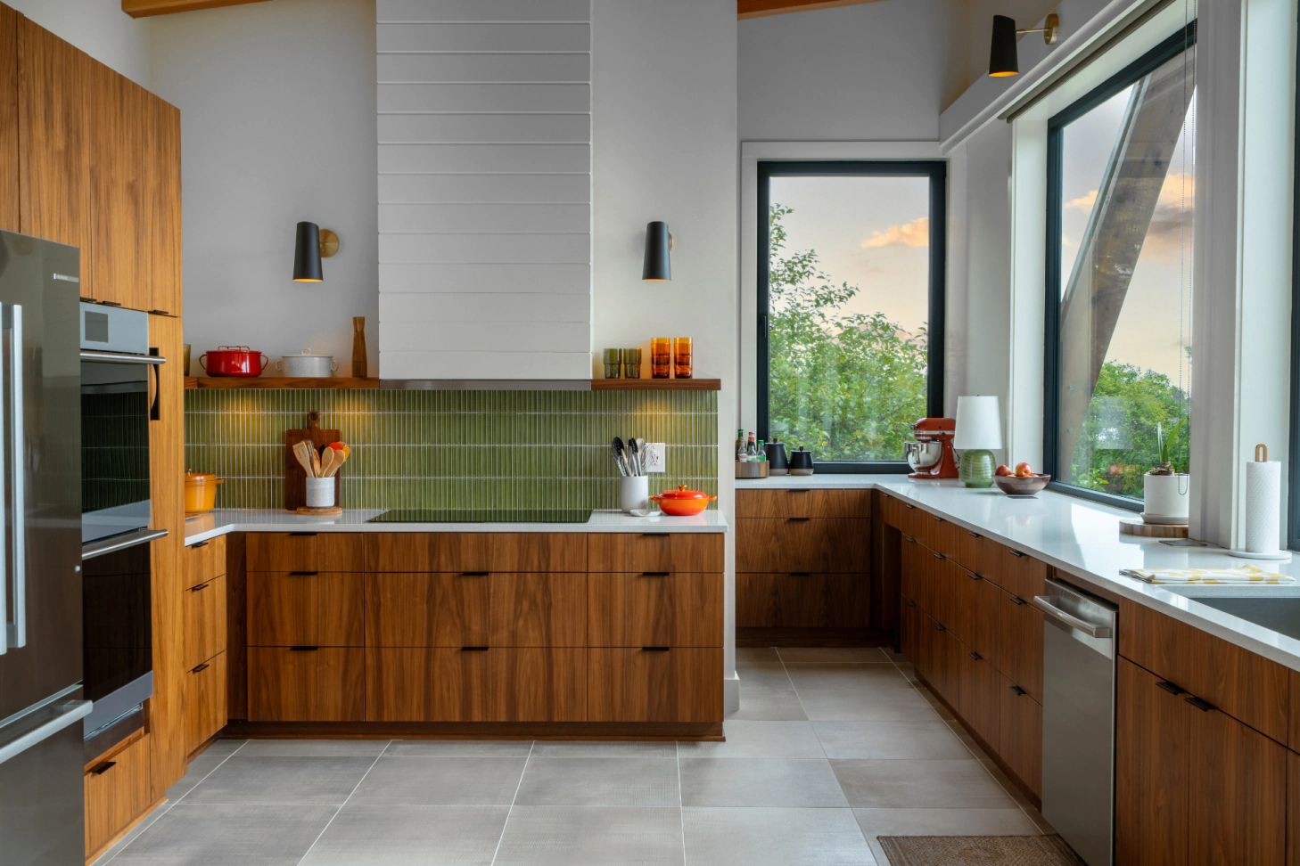 Modern kitchen with wood cabinets, green tile backsplash, and large windows overlooking greenery