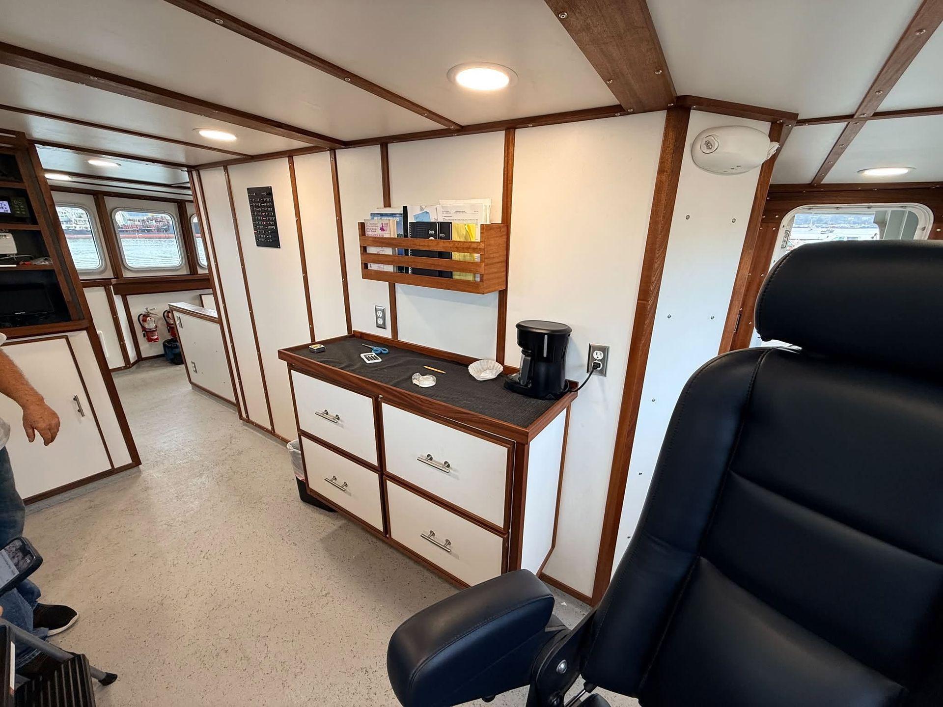 Cozy cabin interior with wood beams, desk, storage cabinets, and a black office chair in the foreground