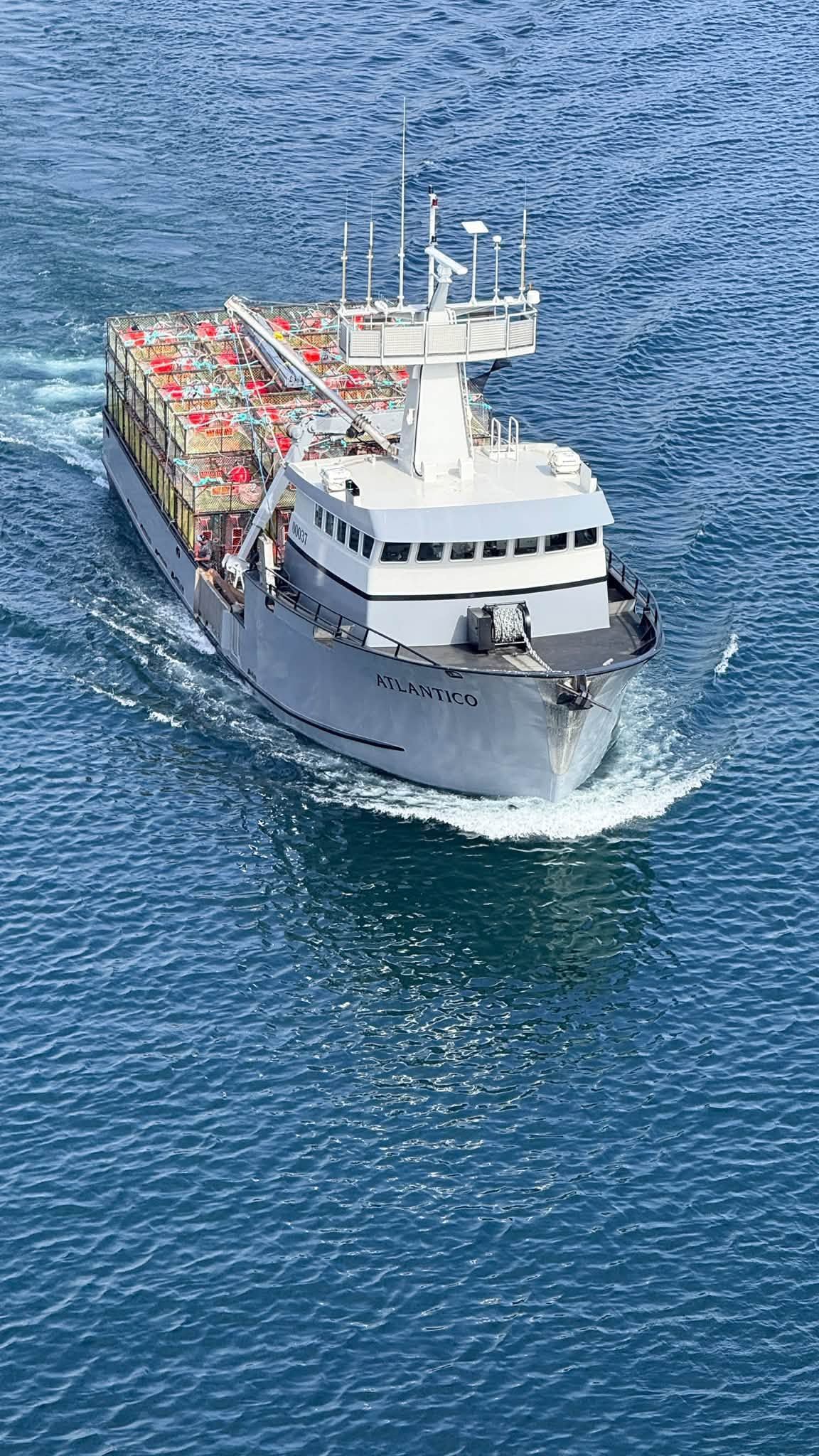 White rescue boat cutting through blue water, loaded with red equipment on deck