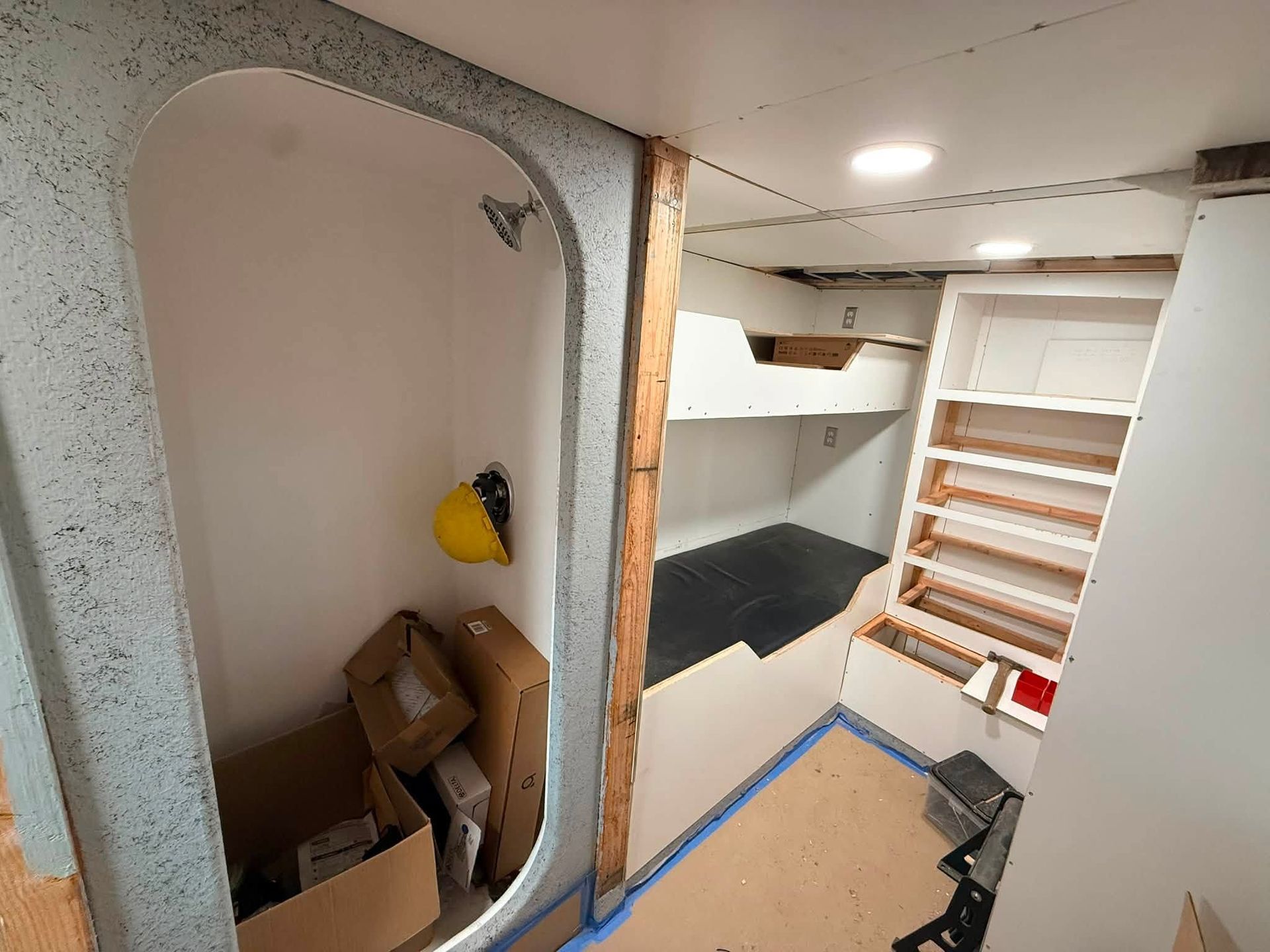 Narrow storage room with shelves, boxes, and exposed framing inside a house under renovation