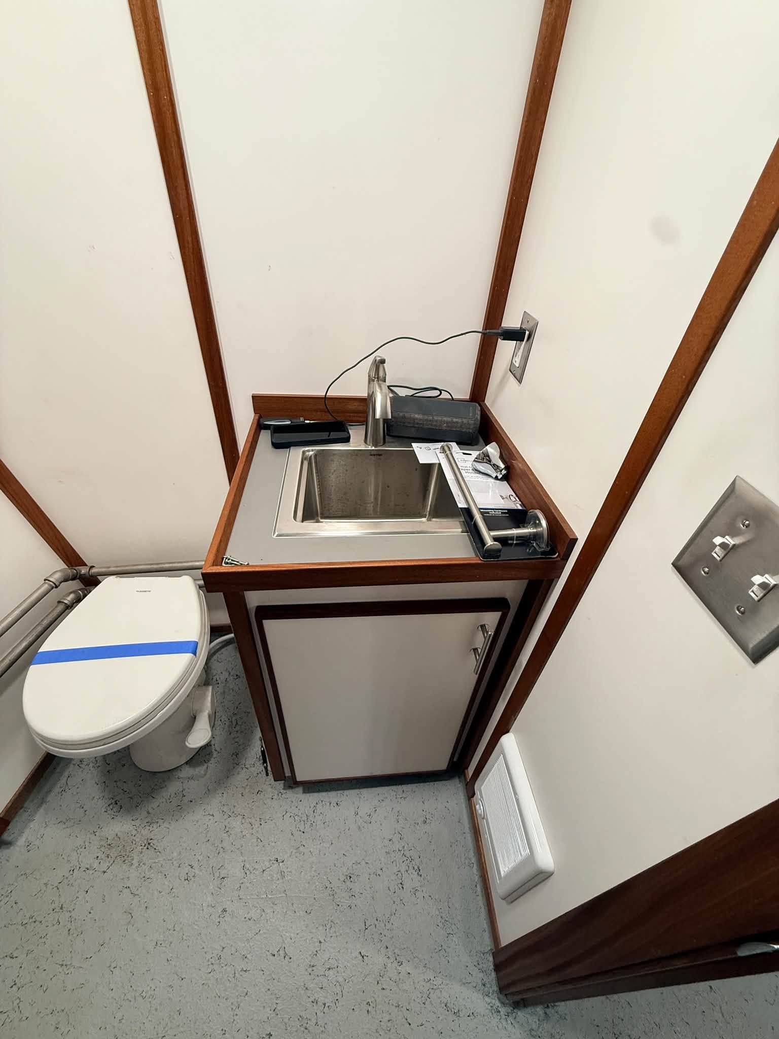 Small restroom with a toilet and compact sink/vanity in a narrow corner.