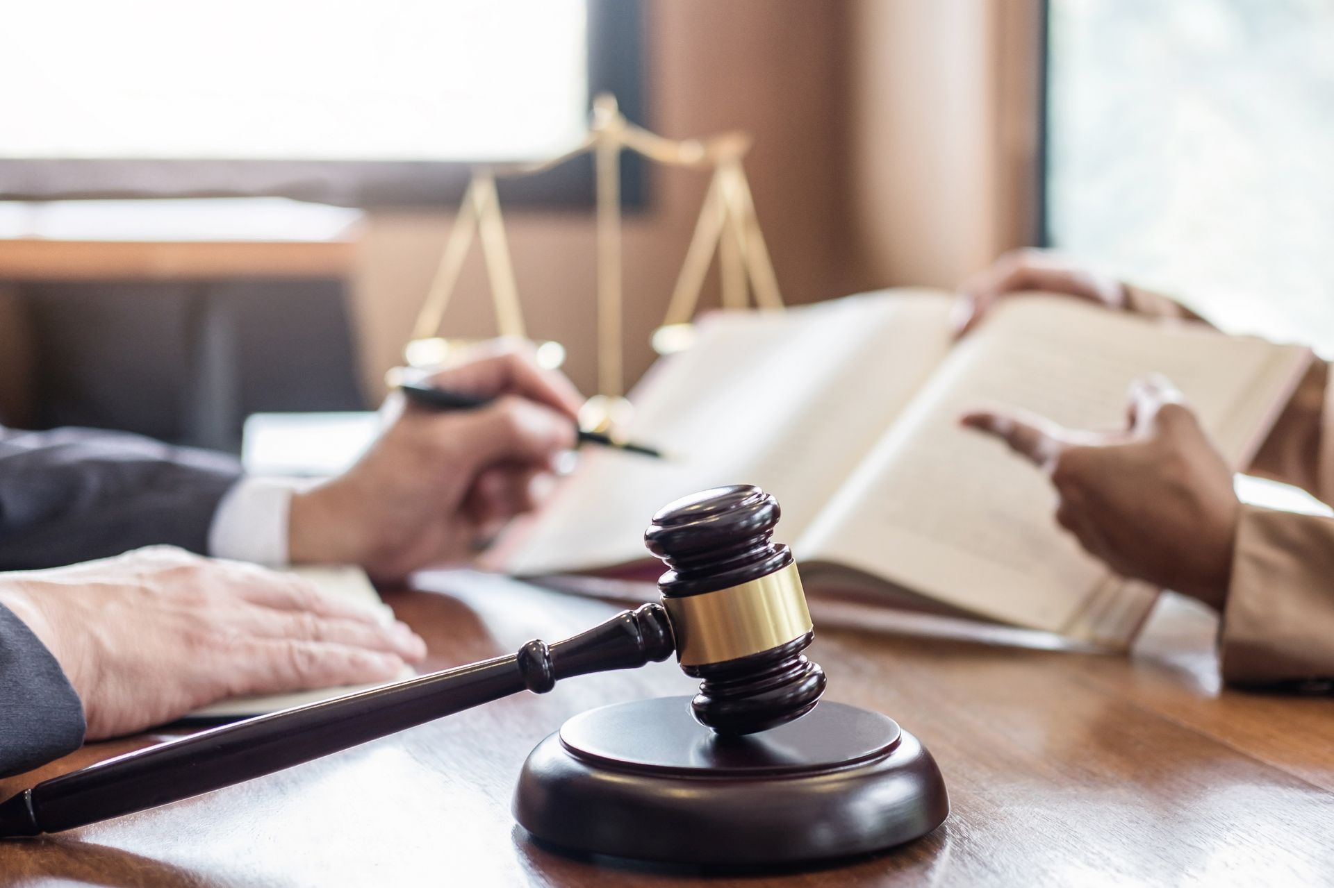 Judge’s gavel on desk with lawyers reviewing documents in a courtroom-style setting