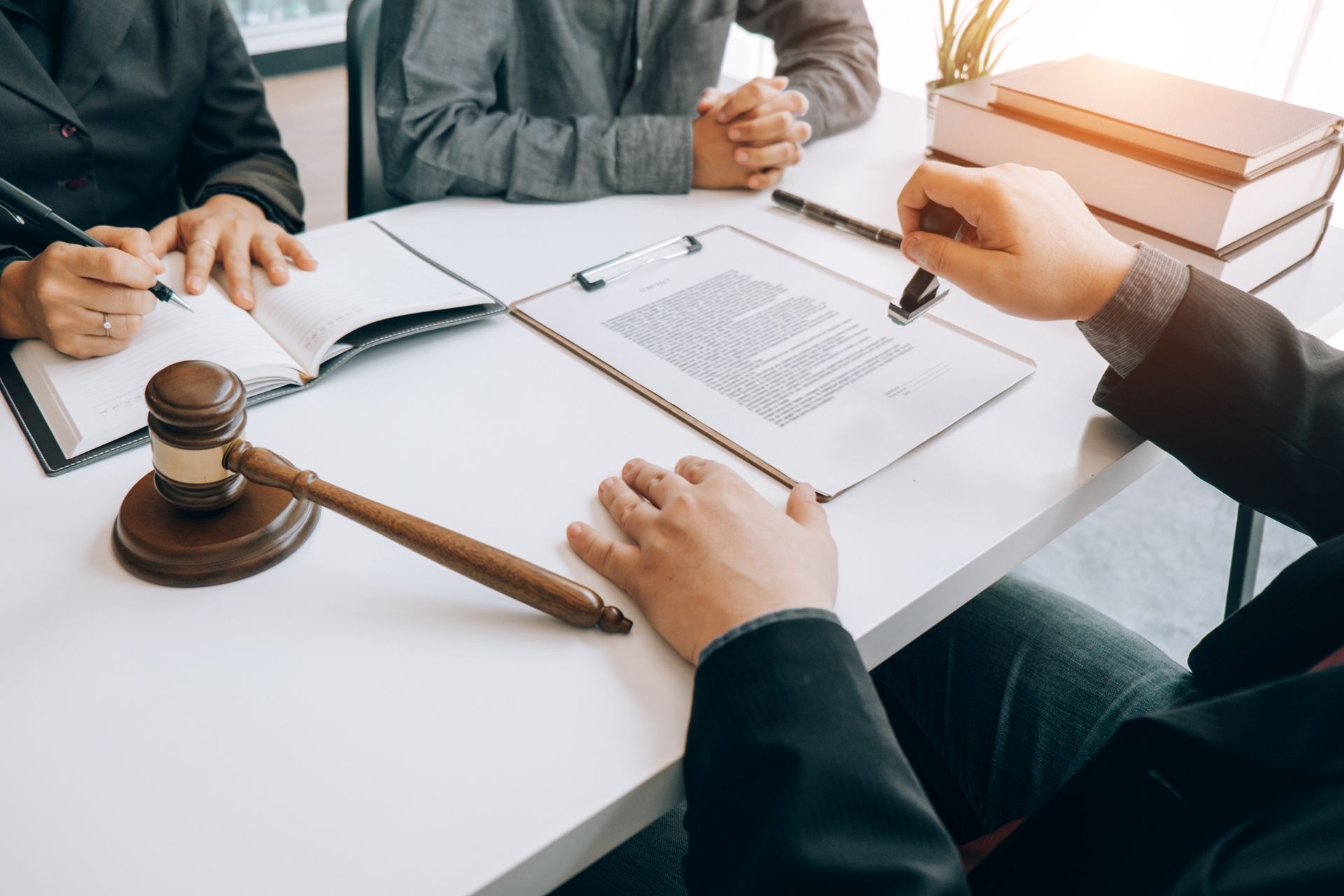 Business meeting with people reviewing documents around a gavel and stacked books on a white table