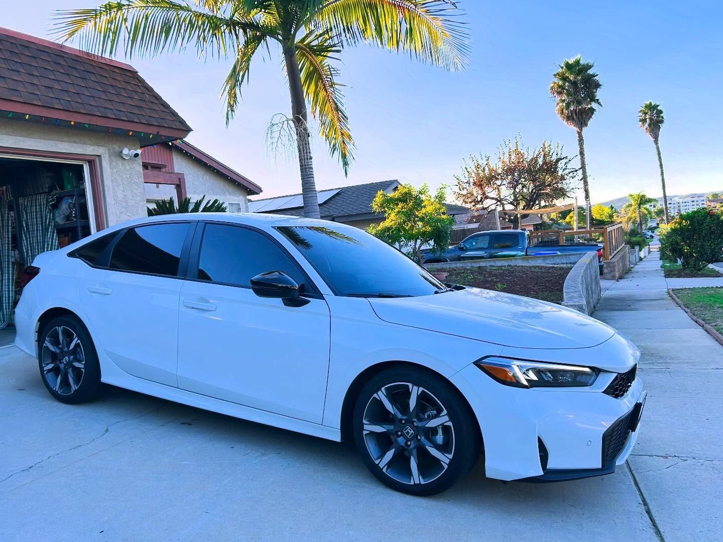 White Honda Civic parked in front of a house on a sunny day.