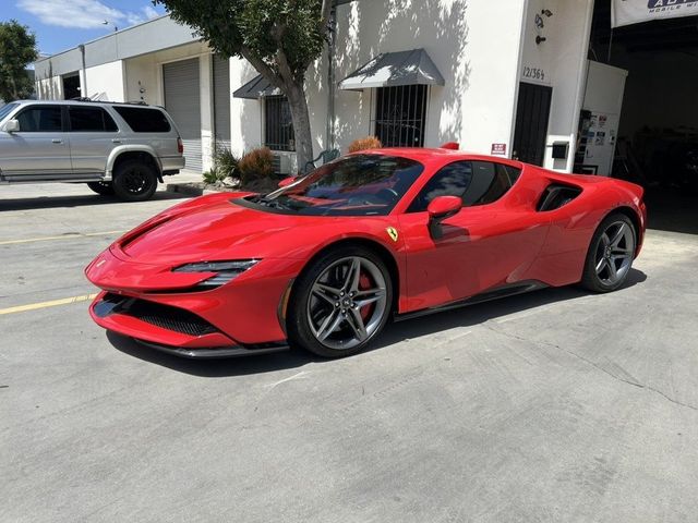 Red Ferrari sports car parked on a sunny street beside a white building