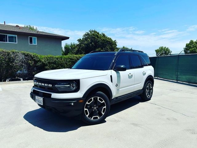 White Ford Bronco parked in a sunny lot, front three-quarter view with black roof and wheels