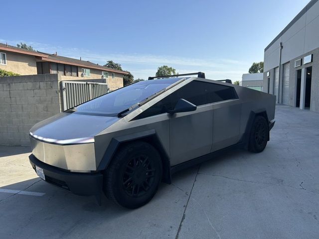 Angular silver Tesla Cybertruck parked in an alley beside a building under clear daylight