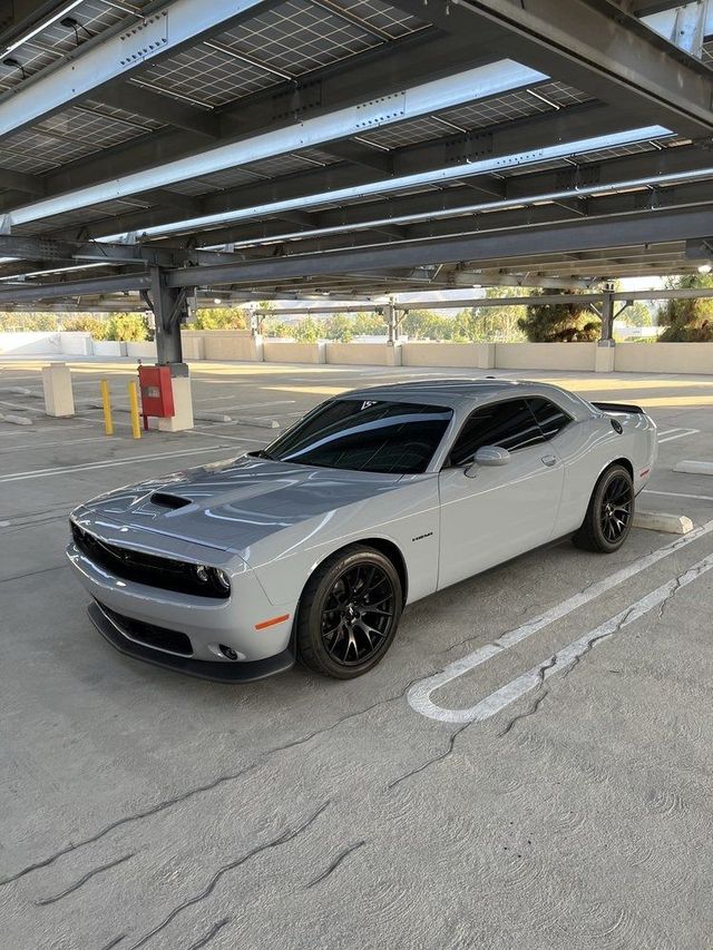 Silver Dodge Challenger parked under a solar carport in a lot