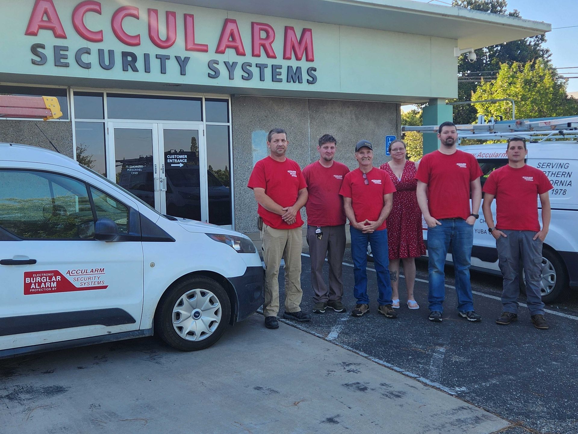 Accularm Security Systems staff pose outside their business. They wear red shirts, stand beside vans. Accularm Security Systems staff pose outside their business. They wear red shirts, stand beside vans.