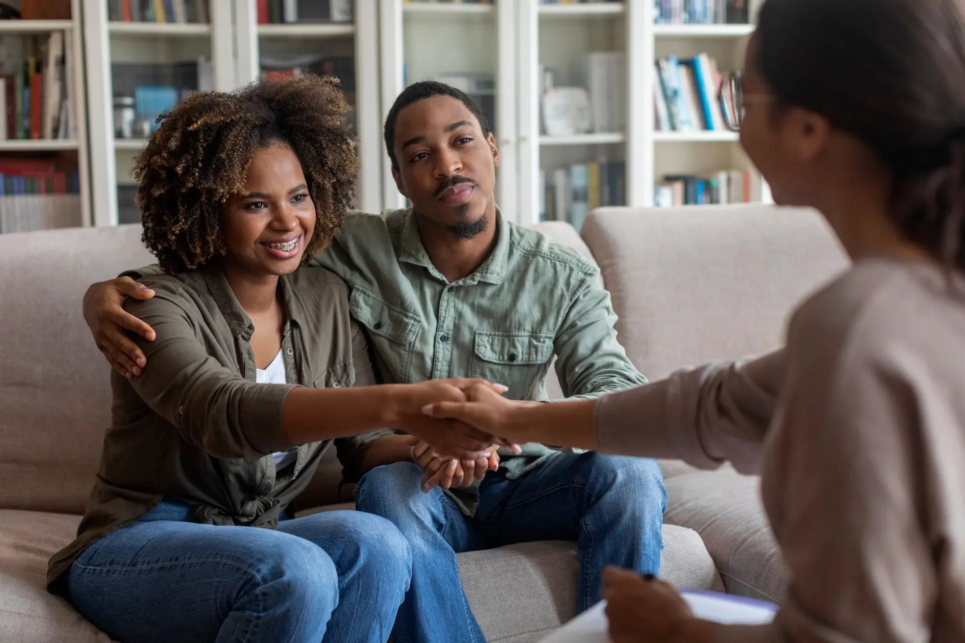 Counselor shaking hands with a couple in a living room during a therapy session