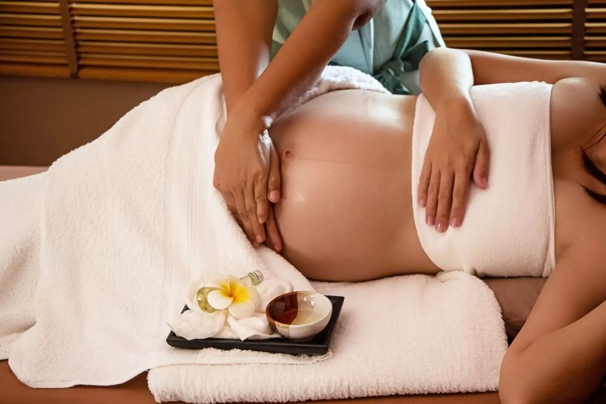 Person receiving a massage on a white towel with spa stones and flowers nearby