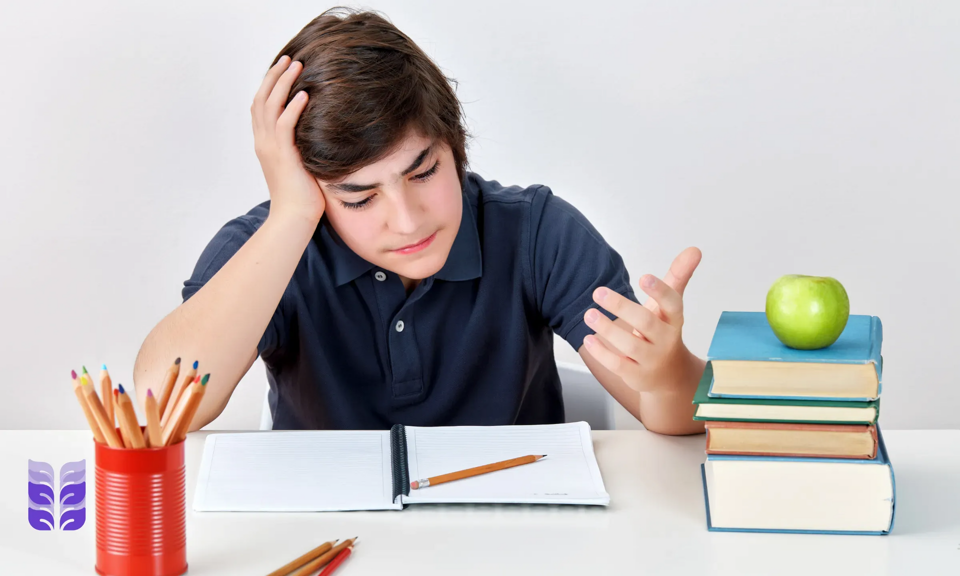 Student looking frustrated at a desk with books, notebook, pencil cup, and an apple stack