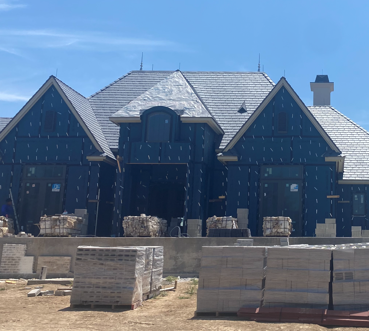 A large blue house with a slate roof is under construction