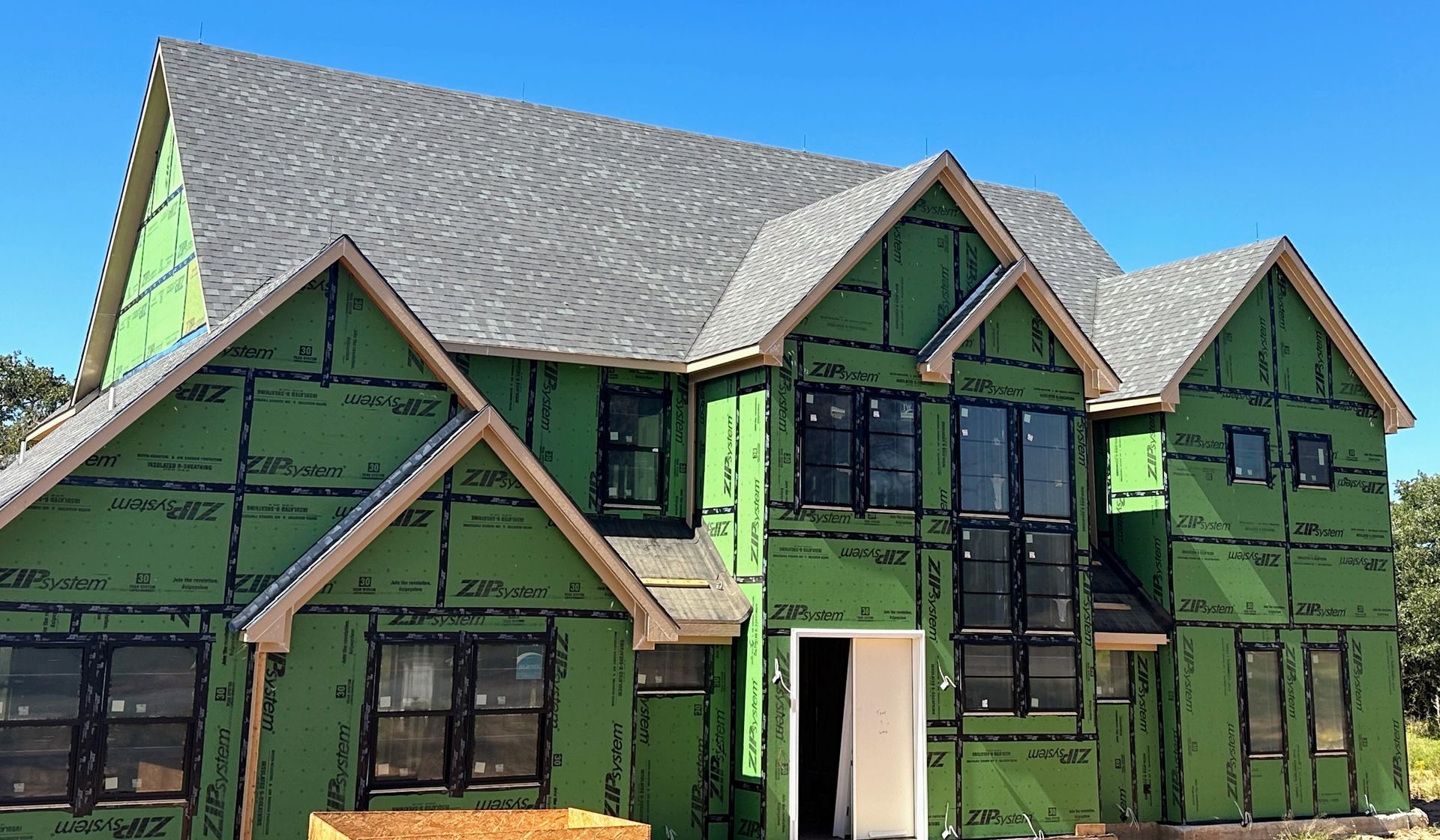 A house is being built with green siding and a gray roof.