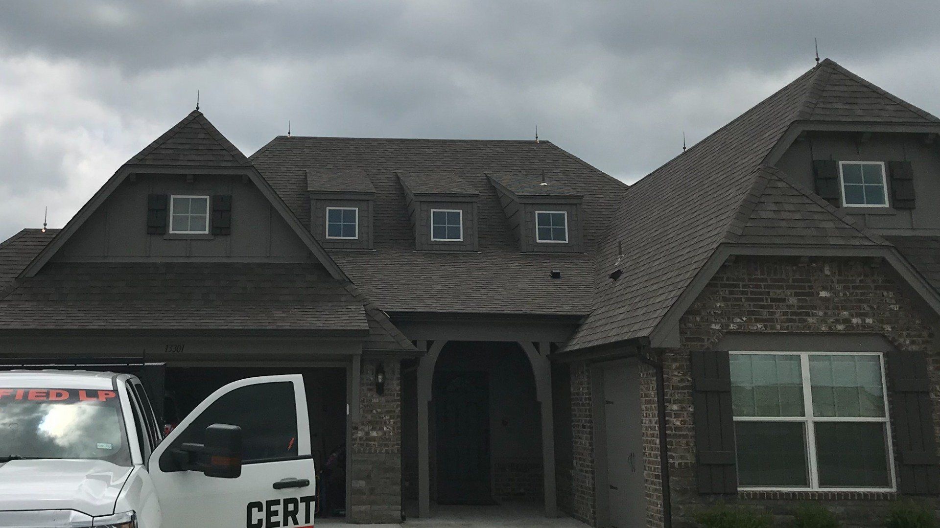 A white truck is parked in front of a large brick house.