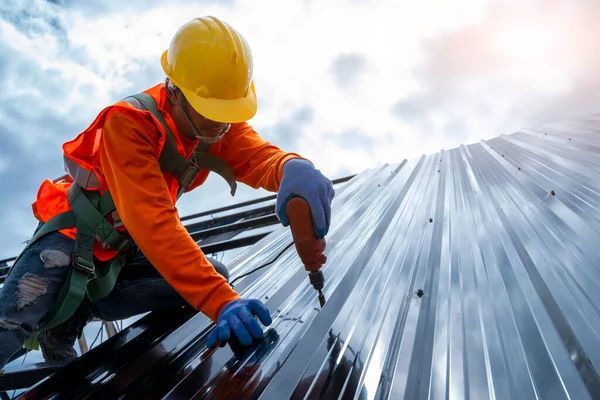 A construction worker is working on a metal roof.