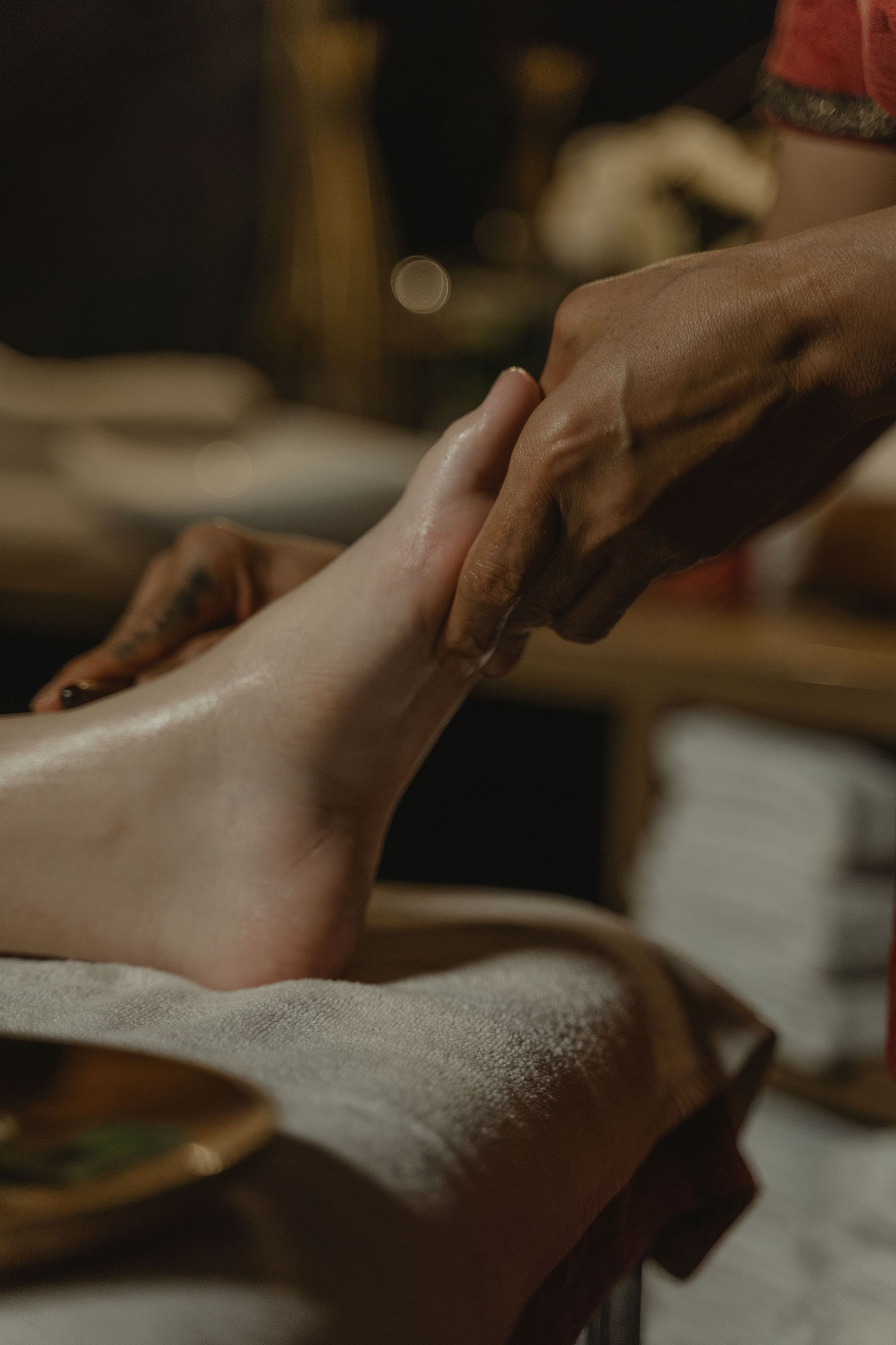 Un kinésithérapeute soutient le pied d’un patient pendant un soin de la cheville, sur une table bleue