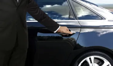 Person opening the door of a dark blue car outdoors