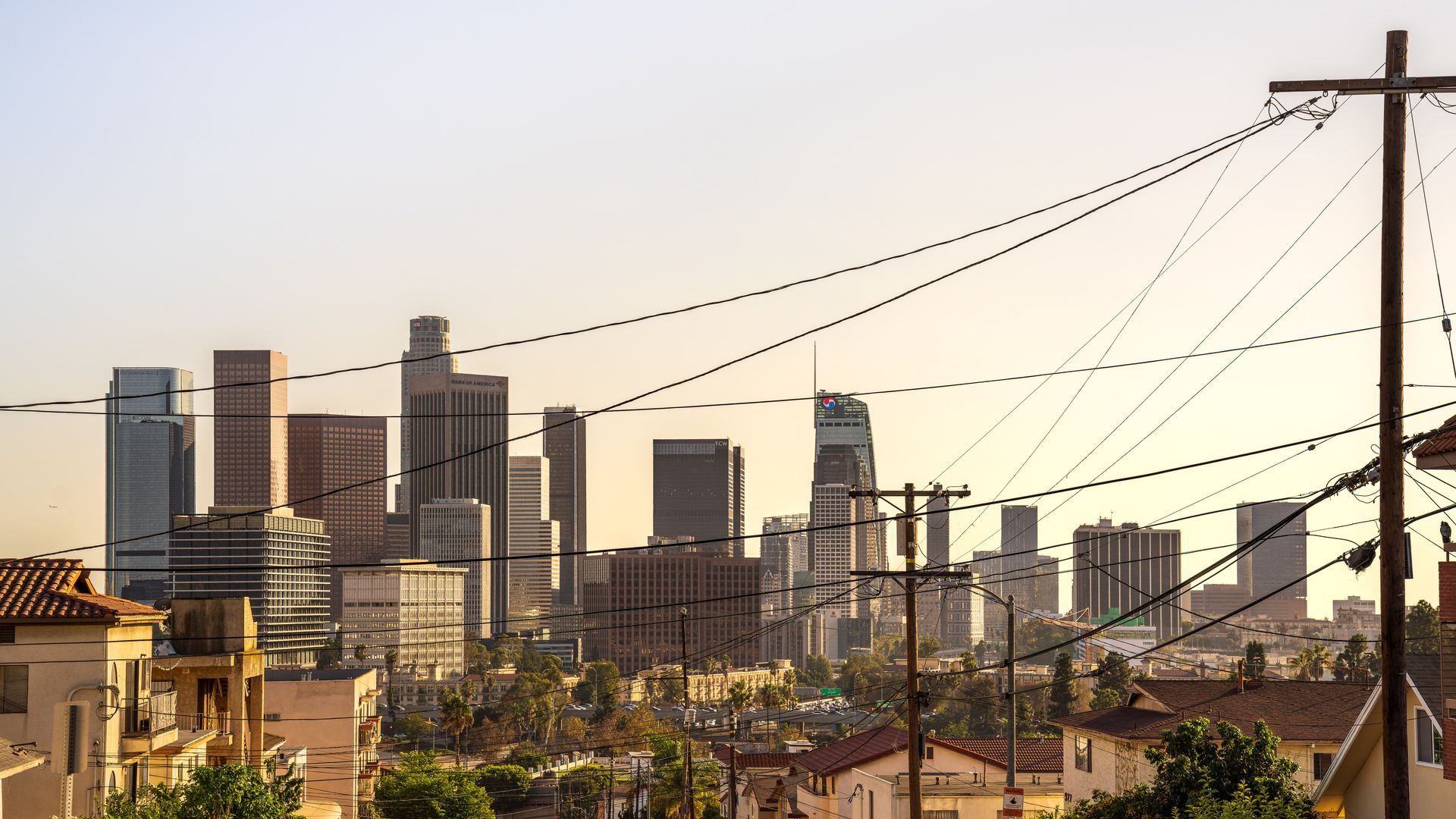 City skyline at sunset with power lines and utility poles in the foreground