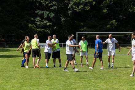 Mensen in sportkleding die met elkaar in gesprek zijn op een grasveld voor een voetbaldoel.