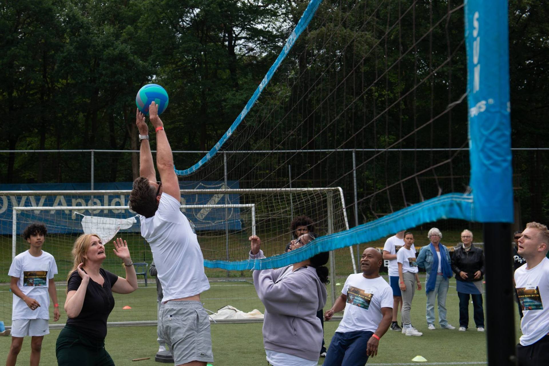 Mensen spelen een volleybalwedstrijd op een buitenveld met een net.