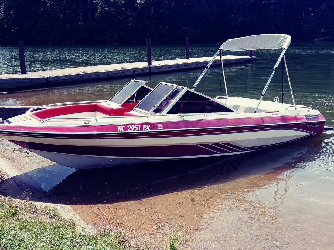Red and white speedboat resting on a boat trailer near the water